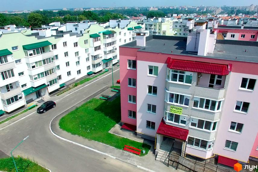 Зовнішній вигляд житлового комплексу Мікрорайон 'Академічний' з кольоровими фасадами. Прибудинкова територія з зеленими зонами та паркувальними місцями.