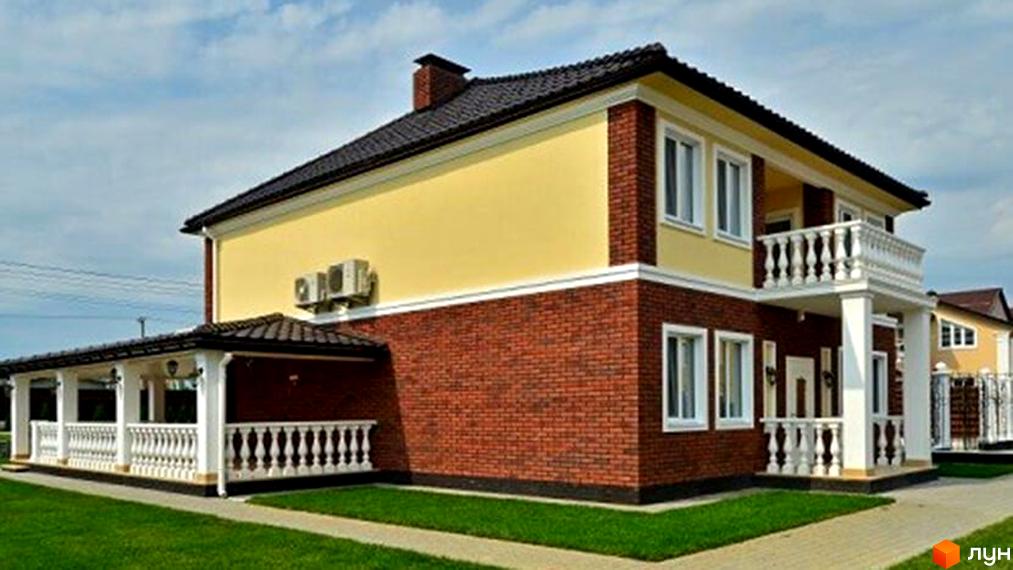 Фото двоповерхового будинку з червоної цегли та жовтою штукатуркою в Котеджному містечку Family House. Навколо будинку зелений газон та тротуарна доріжка.