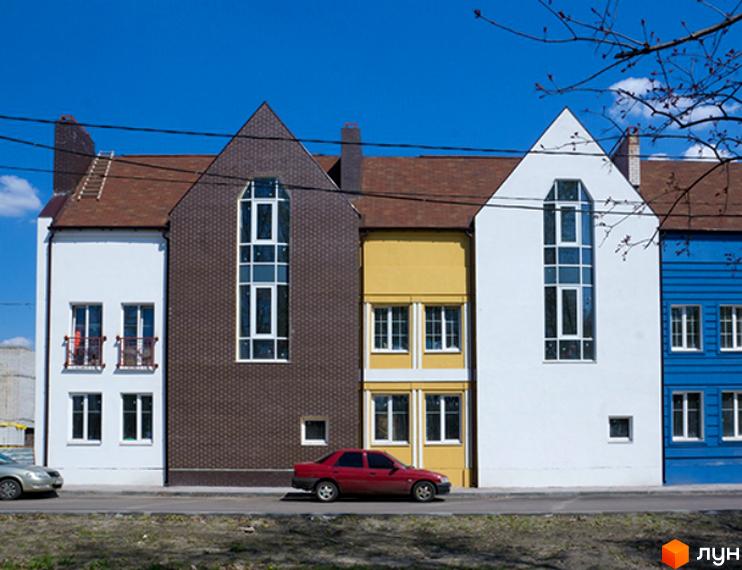 Зовнішній вигляд таунхаусів 'Журавлевская Слобода' з кольоровими фасадами. Прибудинкова територія з автомобілями та зеленими насадженнями.