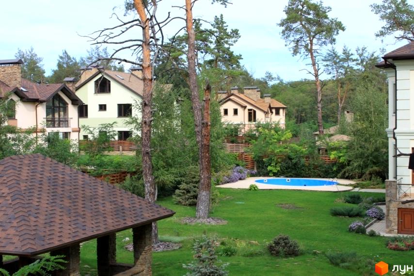 Котеджне містечко Шишкино з будинками в класичному стилі. На території комплексу є басейн та зелені газони.