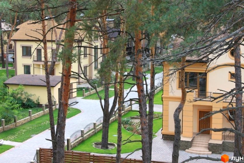 Будинки в Котеджному містечку КМ Шишкино. Житлові будинки з жовтими фасадами, розташовані серед дерев. Доглянута прибудинкова територія з газонами та доріжками.