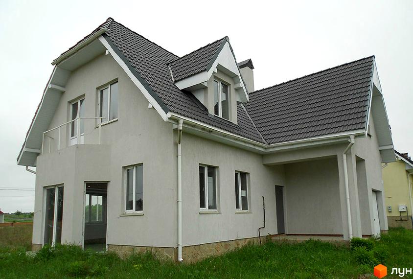 Двоповерховий будинок з сірими стінами та темно-сірим дахом. На території зелена трава.