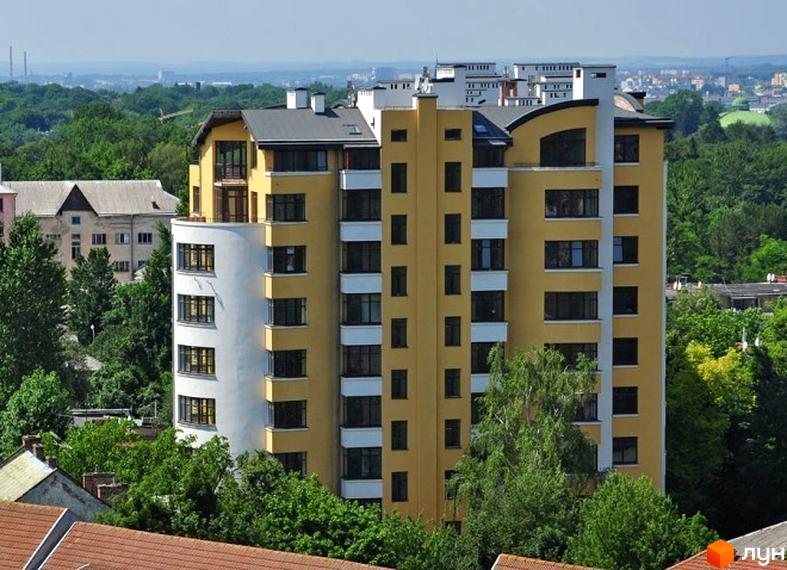 Житловий комплекс на вул. Героїв Крут, 11б: багатоповерховий будинок жовто-білого кольору з вигнутим фасадом, оточений зеленими деревами.