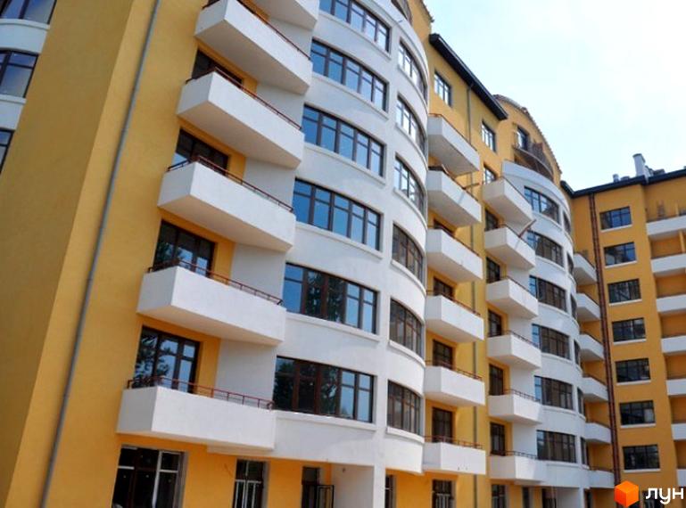 Фасад новобудови на вул. Героїв Крут, 11б: багатоповерховий будинок з жовто-білим оздобленням, вигнутими балконами та вікнами.