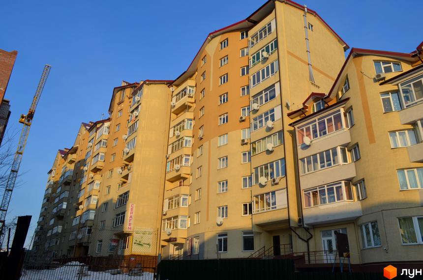 Житловий комплекс на вул. Залізнична, 7, з фасадом жовтого кольору та балконами. На території видно будівельну техніку та огорожу.