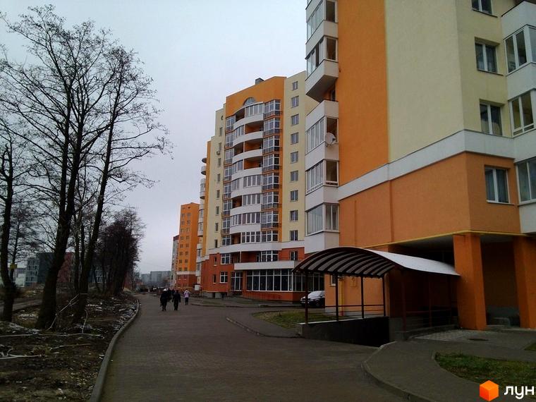 Житловий комплекс на вул. Червоної Калини, 72, 72а: багатоповерхові будинки з помаранчевими та світло-жовтими фасадами, прибудинкова територія з доріжками та деревами.