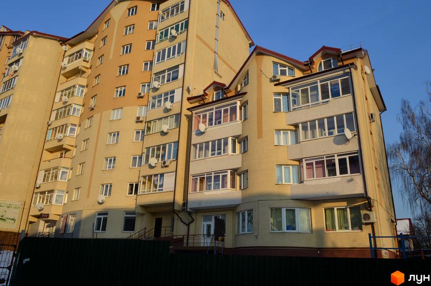 Житловий комплекс на вул. Залізнична, 7 з фасадом, обладнаним балконами та вікнами. Прибудинкова територія з дитячим майданчиком та зеленими насадженнями.