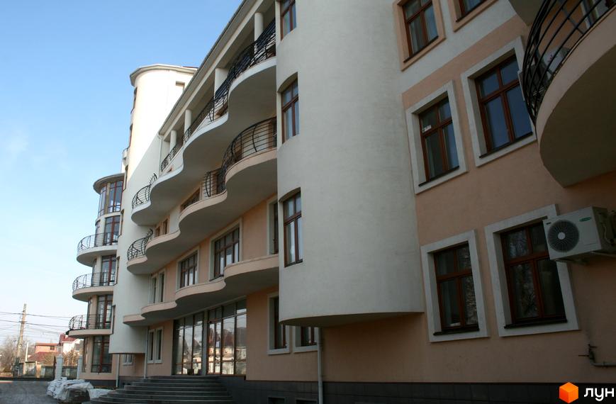 Зовнішній вигляд будівлі ЖК Лазурний берег з балконами та вікнами. На передньому плані сходи та прибудинкова територія.