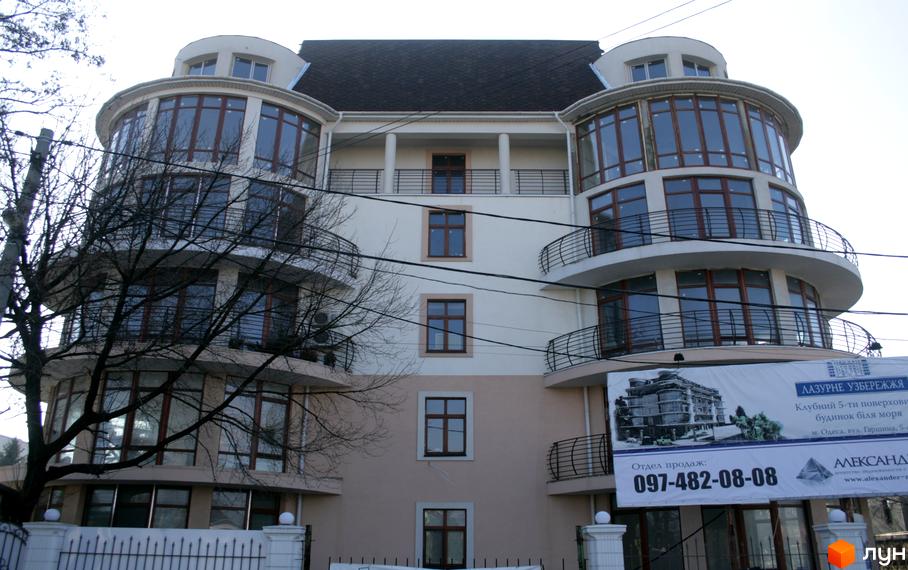 Житловий комплекс Лазурне узбережжя з панорамними вікнами та балконами. На території комплексу є реклама з контактними даними відділу продажу.