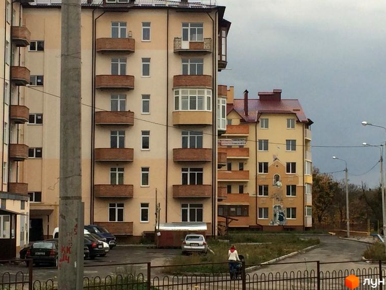 Житловий комплекс Нагірний. Багатоповерхові будинки з балконами та вікнами, прибудинкова територія з дорогою та деревами.