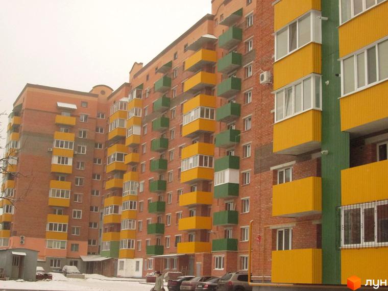 Фасад цегляного житлового комплексу на вулиці Вузька, 7а, з балконами жовтого та зеленого кольорів. Навколо будинку засніжена територія з автомобілями.