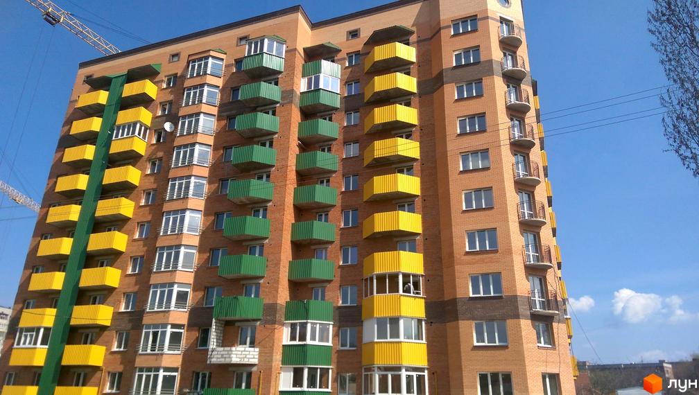 Багатоповерховий цегляний будинок з яскравими жовтими та зеленими балконами. Зовнішній вигляд новобудови на вулиці Вузька, 7а.
