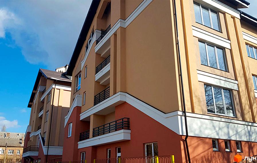 Житловий комплекс Comfort Club. Фасад новобудови з балконами та великими вікнами. Ззовні будинок оздоблений бежевими та червоними елементами.
