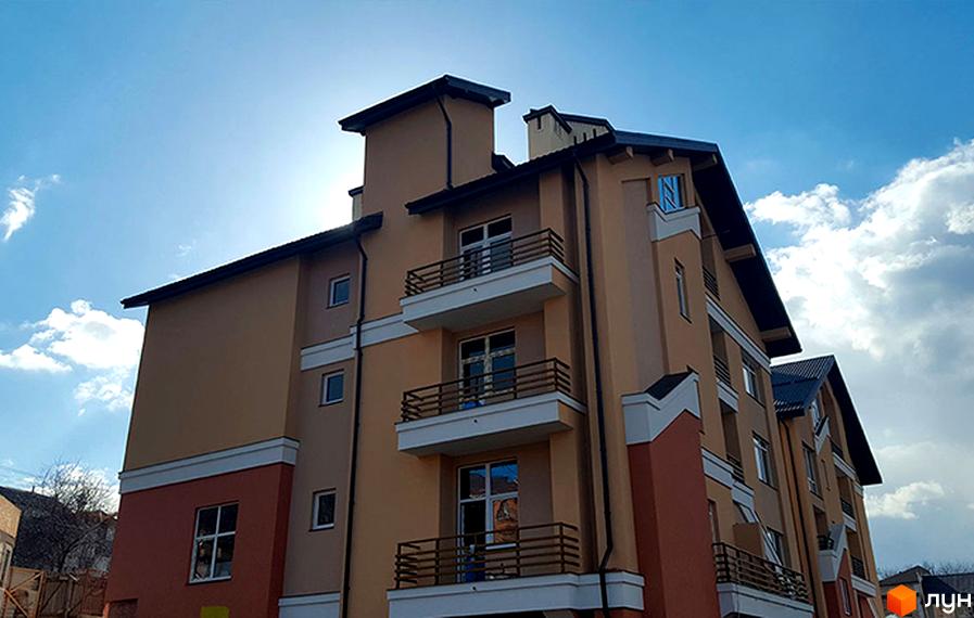 Житловий комплекс Comfort Club - фасади будівель з балконами та вікнами на тлі блакитного неба з хмарами. Зовнішній вигляд новобудови.