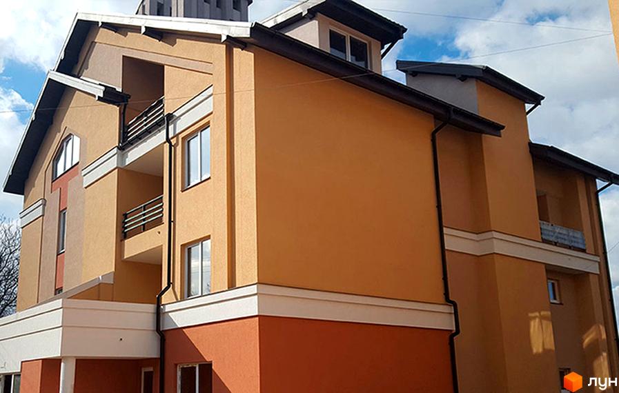 Фасад житлового комплексу Comfort Club з помаранчевими та білими елементами. Будинок має кілька поверхів, балкони та вікна.