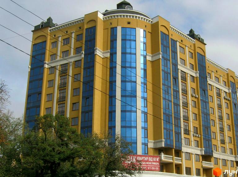 Зовнішній вигляд жовтої новобудови з синіми вікнами на вулиці Івана Банка (Коваля), 2. Будинок має багатоповерхову структуру з виступаючими елементами та балконами.