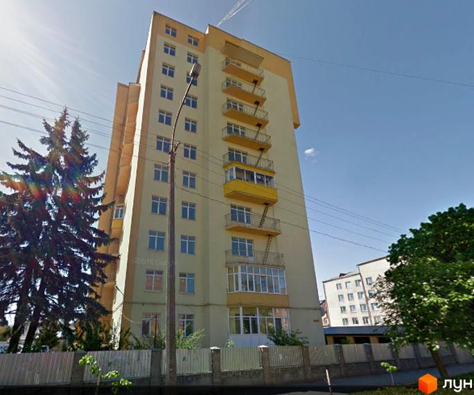 Багатоповерховий житловий комплекс на вул. Струтинської, 2в, світло-жовтого кольору з жовтими балконами. Поруч зелені насадження та огорожа.