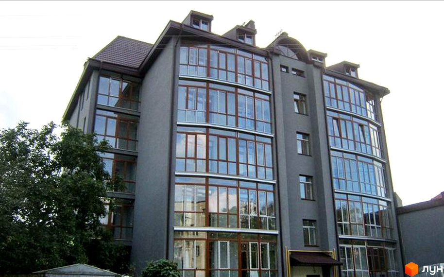 Житловий комплекс на вул. Кутова, 5 має темно-сірий фасад та великі панорамні вікна. Поруч з будинком розташовані зелені дерева.