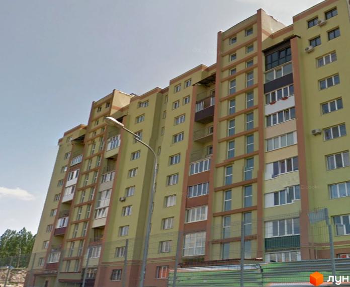 Житловий комплекс на вул. Богоявленська, 5. Світло-жовтий багатоповерховий будинок з коричневими акцентами, вікнами та балконами. Поруч вуличний ліхтар.