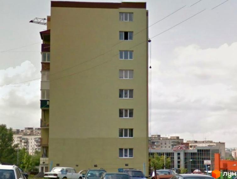 Житловий комплекс на вул. Богоявленська, 5: високий будинок світлого кольору з балконами та прилеглою парковкою.