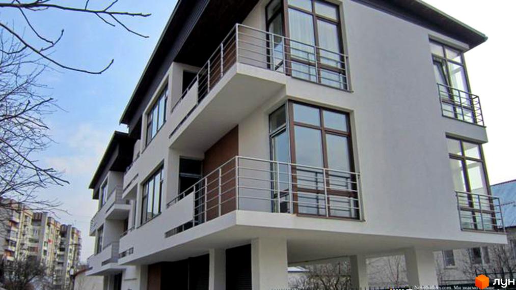 Біла багатоповерхова новобудова з балконами та металевими поручнями на вул. Жнивна / вул. Варшавська. Навколо розташовані дерева та інші житлові будинки.