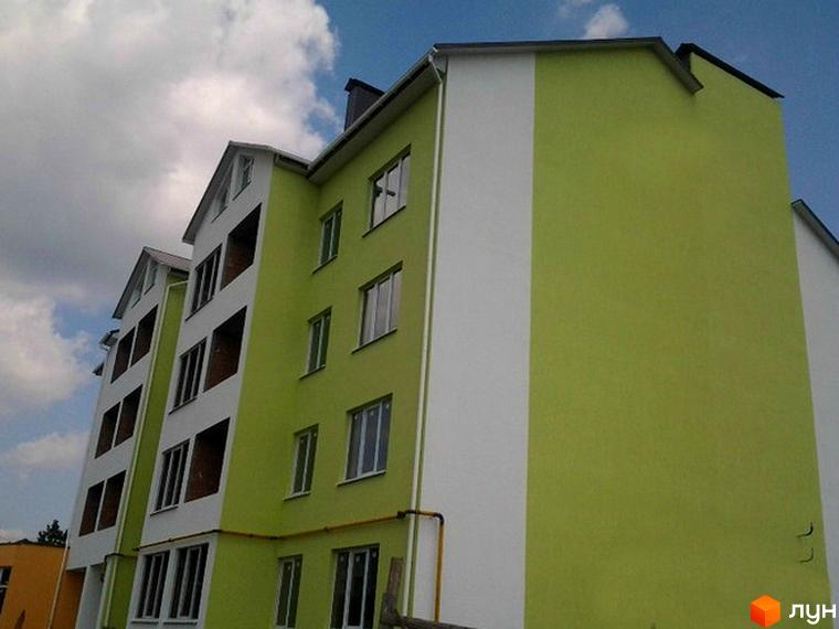 Новобудова на вул. Заводська, 58 з багатоповерховим фасадом світло-зеленого та білого кольорів, вікнами та балконами.