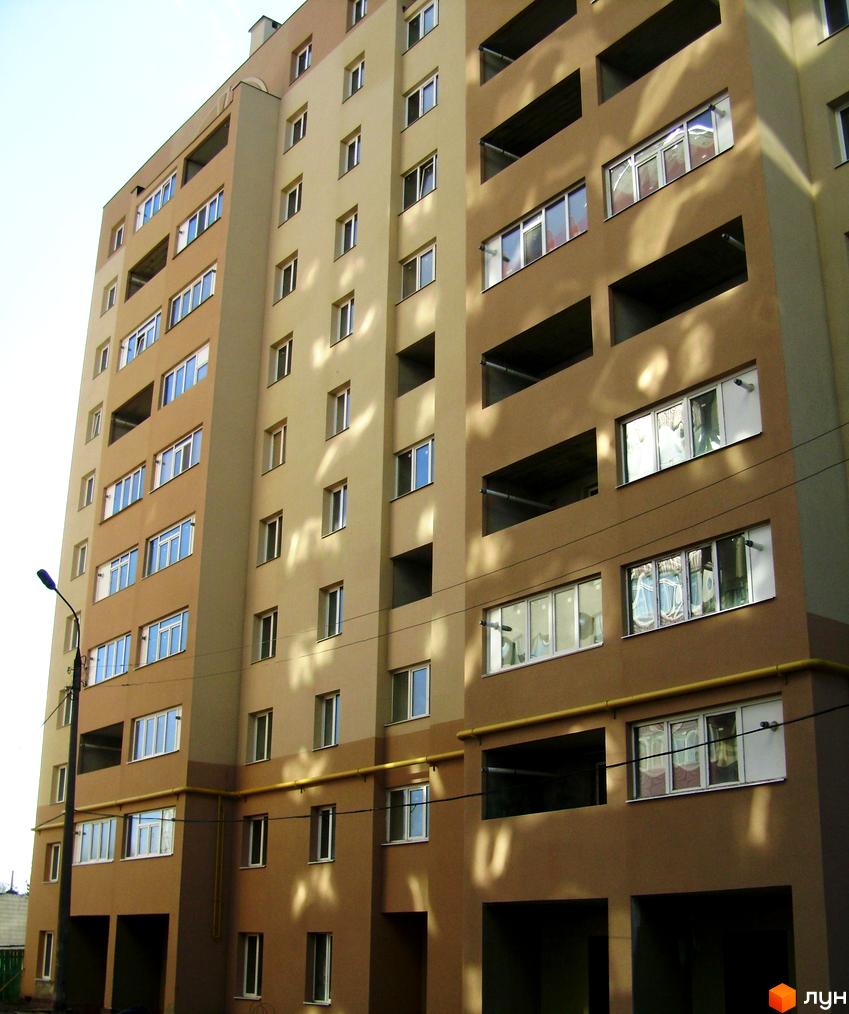 Багатоповерховий житловий будинок бежево-коричневого кольору з вікнами та балконами. Розташований на просп. Свободи (вул. Прокоф'єва), 16, з жовтими трубами на фасаді.