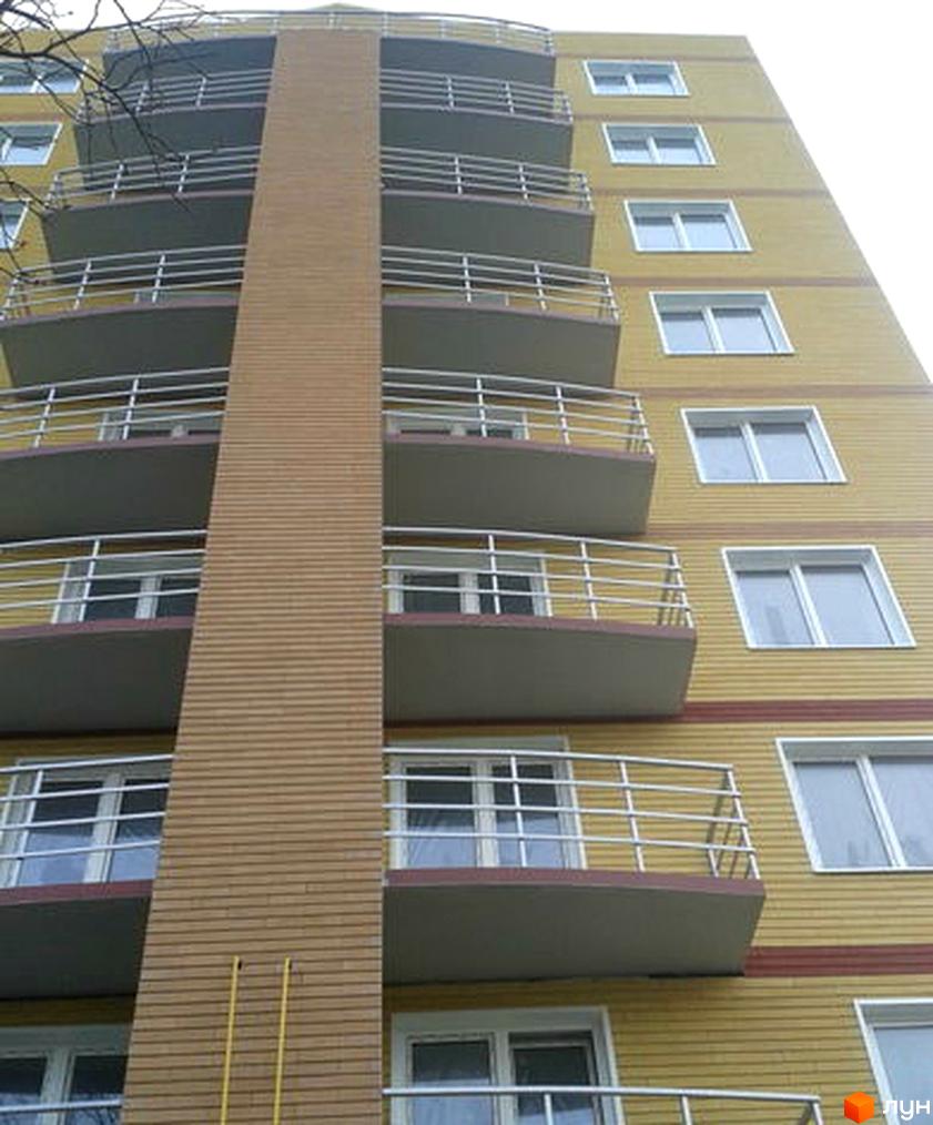 Зовнішній вигляд новобудови ЖК Небос Хилл з балконами та вікнами на жовтому фасаді. Будівельний проєкт з багатоповерховими секціями.