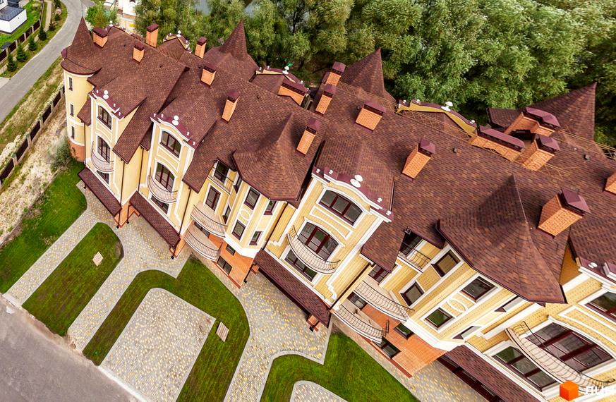 Клубний будинок „Хутір Ясний“ з коричневим дахом та жовтими стінами. Навколо будинку доглянута прибудинкова територія з газоном та бруківкою.