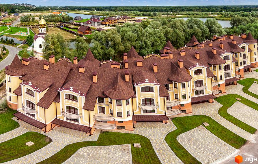 Клубний будинок Хутір Ясний з коричневими дахами та жовтими стінами. Навколо будинку доглянута прибудинкова територія з зеленими газонами та бруківкою.