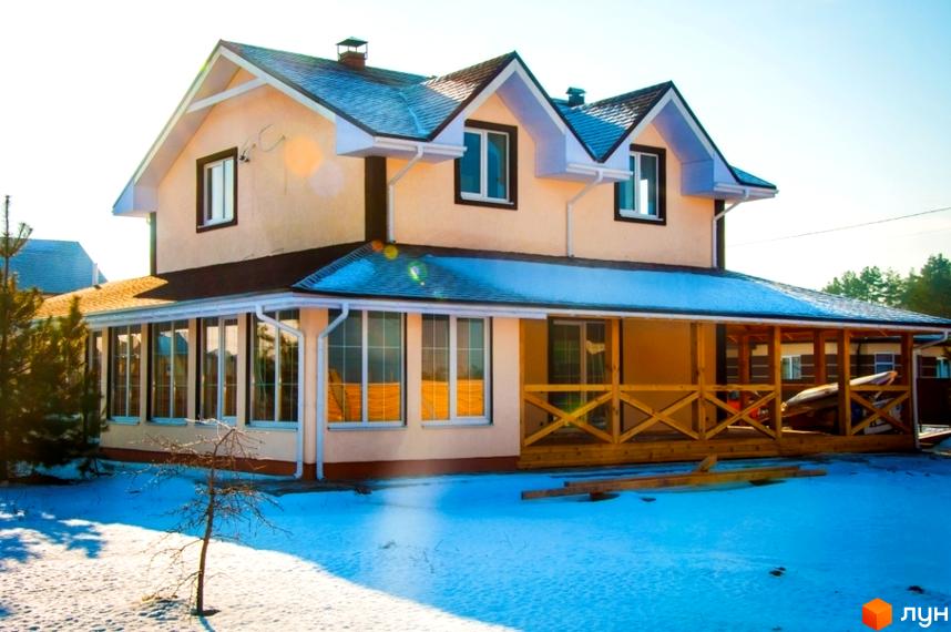 Двоповерховий будинок Котеджного містечка HappyTown з бежевими стінами, темним дахом та великими вікнами. Прибудинкова територія вкрита снігом.