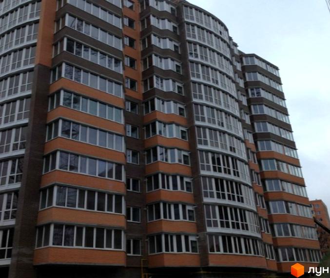 Житловий комплекс Рів'єра - багатоповерховий будинок з цегляним фасадом та великою кількістю скляних балконів. Зовнішній вигляд будівлі.