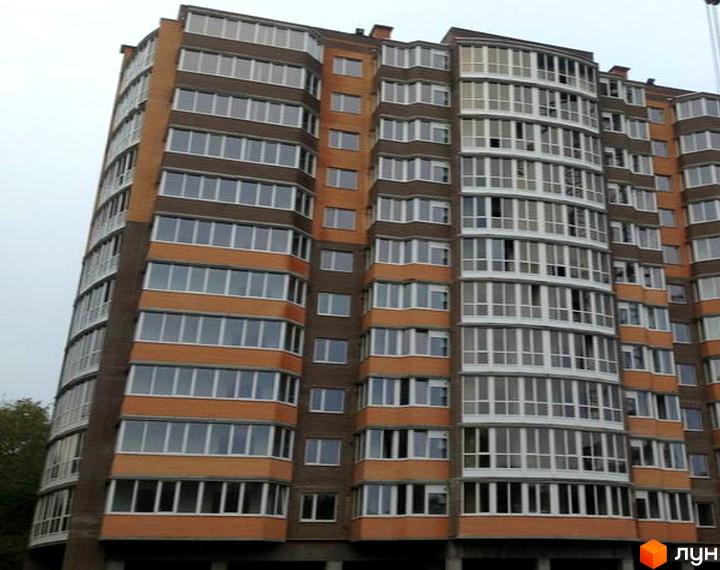 Житловий комплекс Рів'єра - багатоповерховий будинок з коричневою та помаранчевою цегляною обробкою та великою кількістю вікон. Фасад будівлі має вигнуту форму з численними балконами.