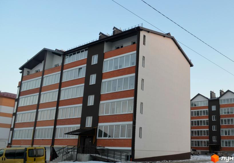 Житловий комплекс Гарантія. Зовнішній вигляд новобудови з цегляним фасадом та великими вікнами. Поруч видно іншу будівлю та елементи прибудинкової території.