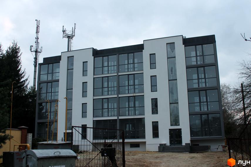 Зовнішній вигляд фасаду новобудови ЖК Озерний з великими панорамними вікнами. Навколо будівлі видно прибудинкову територію з елементами благоустрою.