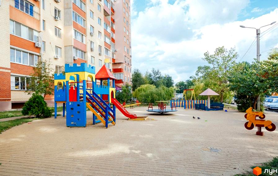 Зовнішній вигляд будинку житлового комплексу ЖК Райдужний з дитячим майданчиком та прибудинковою територією.