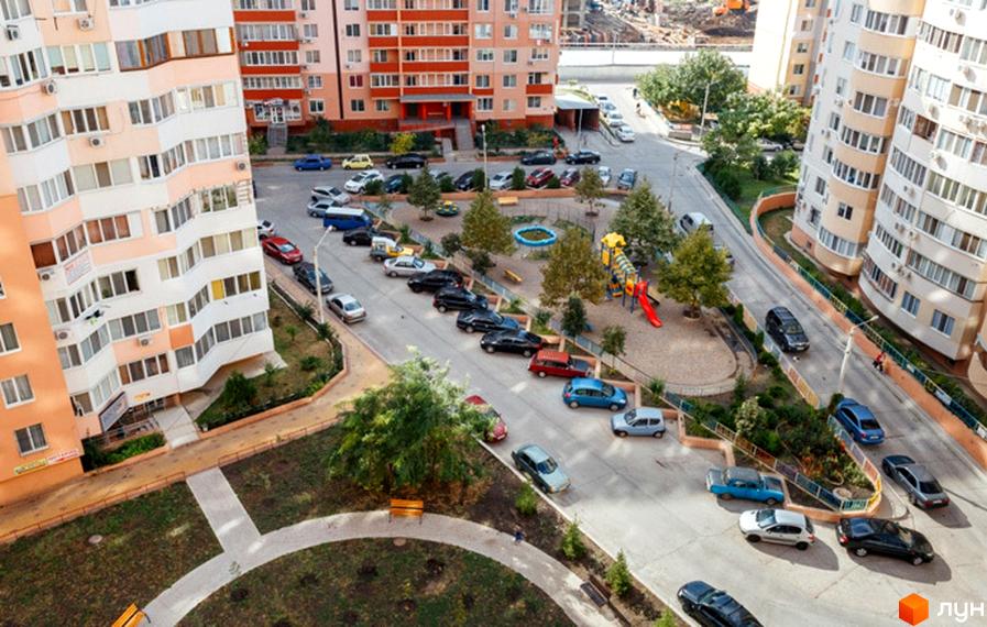 Житловий комплекс Райдужний з сучасними фасадами та прибудинковою територією з дитячим майданчиком і зеленими насадженнями.