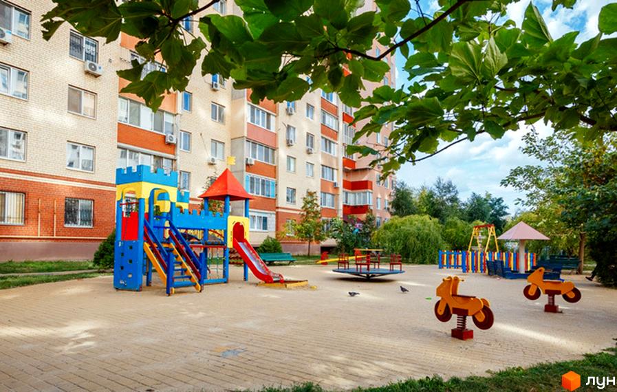Зовнішній вигляд житлового комплексу Райдужний з дитячим майданчиком та прибудинковою територією.