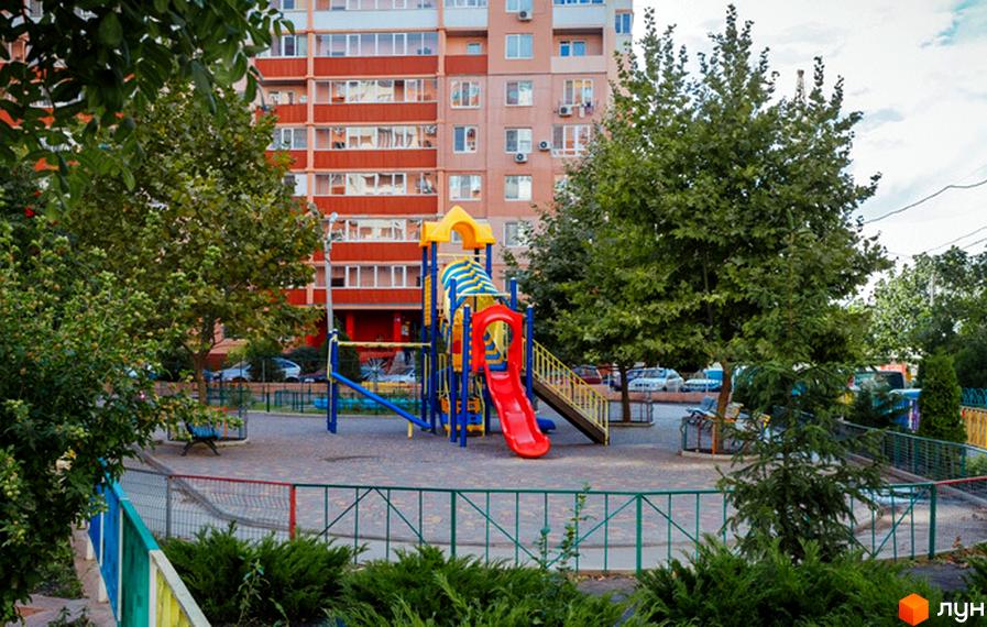 Житловий комплекс ЖК Райдужний з дитячим майданчиком на прибудинковій території та зеленими насадженнями.