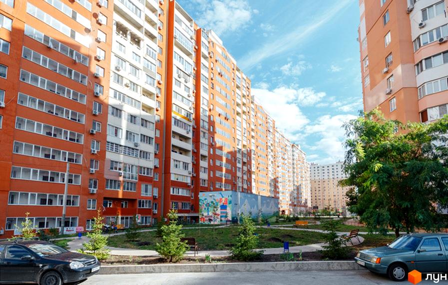 Житловий комплекс Райдужний з яскравими фасадами та прибудинковою територією з зеленими насадженнями та лавками.