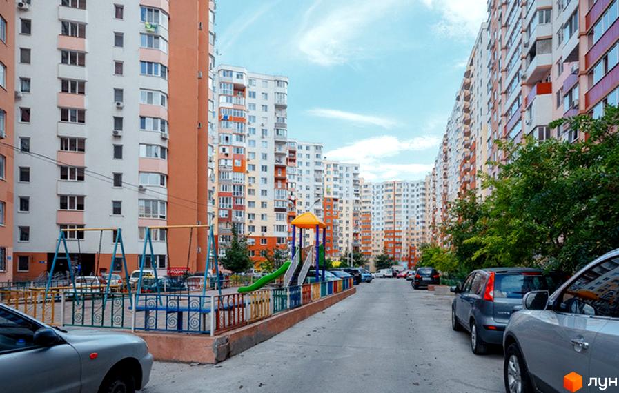 Житловий комплекс Райдужний - багатоповерхові будинки з яскравими фасадами та дитячим майданчиком. Затишний двір з деревами та місцями для паркування.