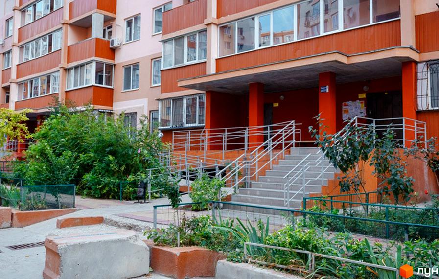 Зовнішній вигляд будинку ЖК Райдужний з балконами та вікнами. Прибудинкова територія з зеленими насадженнями та сходами.