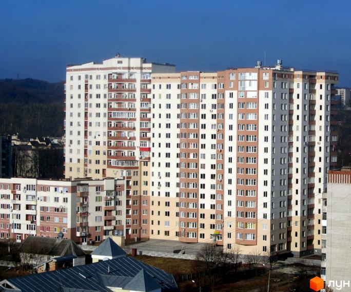 Житловий комплекс на вул. Панча, 18б, складається з будинків з білими та коричневими фасадами. Видно прибудинкову територію та дерева.