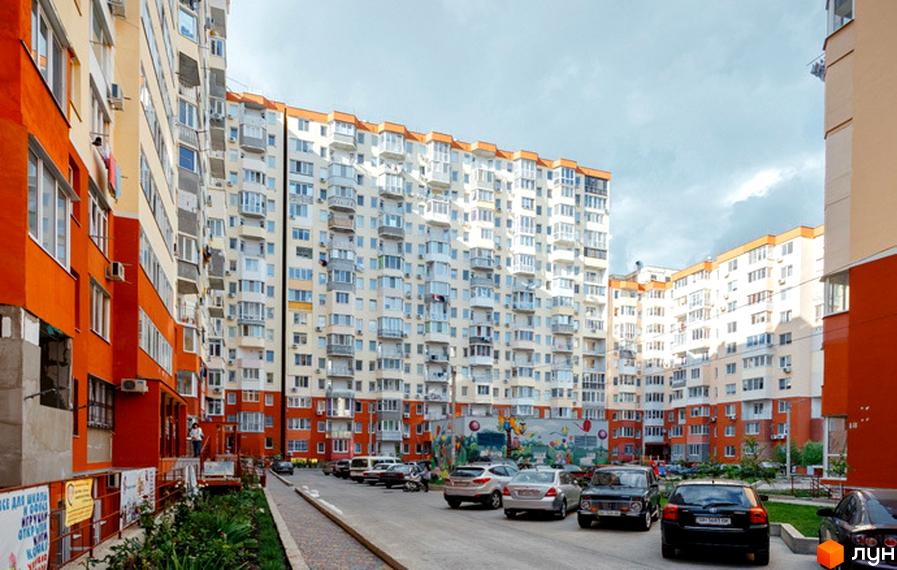 Житловий комплекс Райдужний: багатоповерхові будинки з яскравими фасадами та затишний внутрішній двір з місцями для паркування. Фото новобудови.