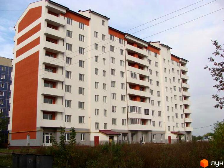 Висотна новобудова з білими фасадами та помаранчевими вставками. На території комплексу є зелені насадження та низькоросла рослинність.