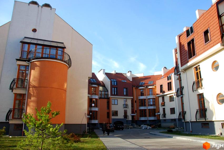 Вул. Гординських, 4а: будинки зі світлими фасадами, помаранчевими акцентами, червоними дахами, балконами. Прибудинкова територія з доріжками, зеленню.