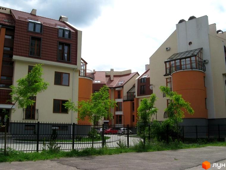 Новобудова на вул. Гординських, 4а з бежевими фасадами, коричневими дахами та округлим балконом. Територія озеленена, обгороджена чорним парканом.