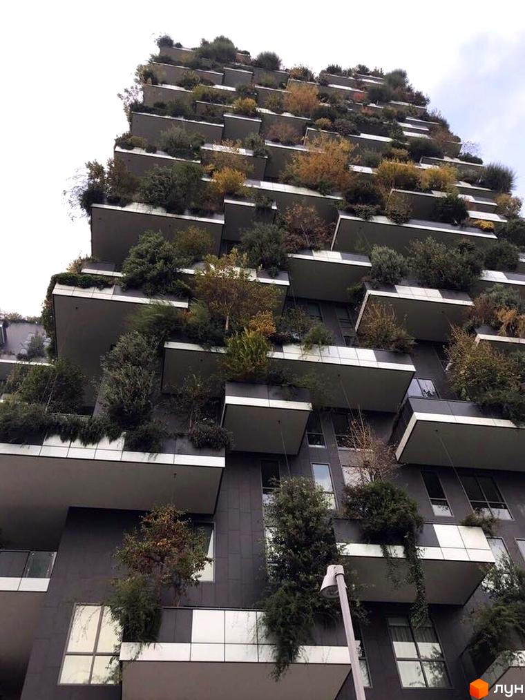 Житловий комплекс Панська Вертикаль з балконами, засадженими деревами та кущами. Зовнішній вигляд будівлі з численними терасами та зеленню.
