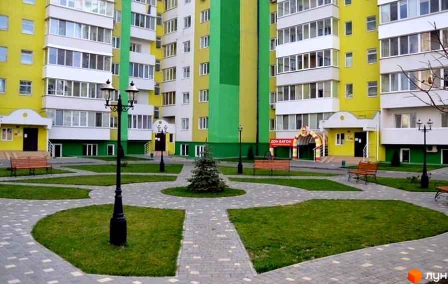 Житловий комплекс ЖМ Острови з яскравими фасадами. Прибудинкова територія з газоном, лавками та пішохідними доріжками.