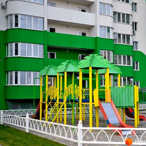 Житловий комплекс ЖМ Острови з зеленими фасадами та дитячим майданчиком на прибудинковій території.